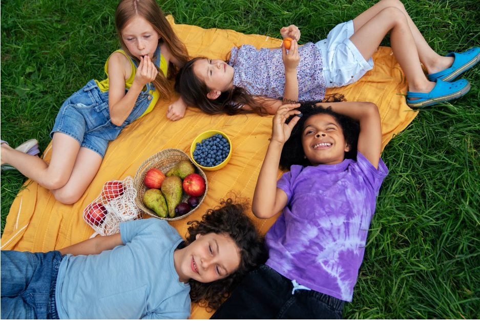 Деца от лагера Лъки Банско Кидс Камп ядат плодове по време на пикник.