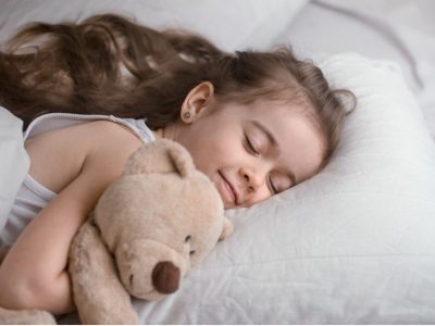 Малко момиче спи, гушнало плюшеното си мече