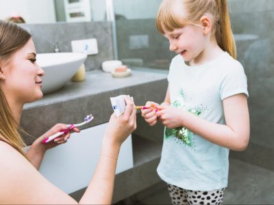 Майка слага паста за зъби на четката на детето си