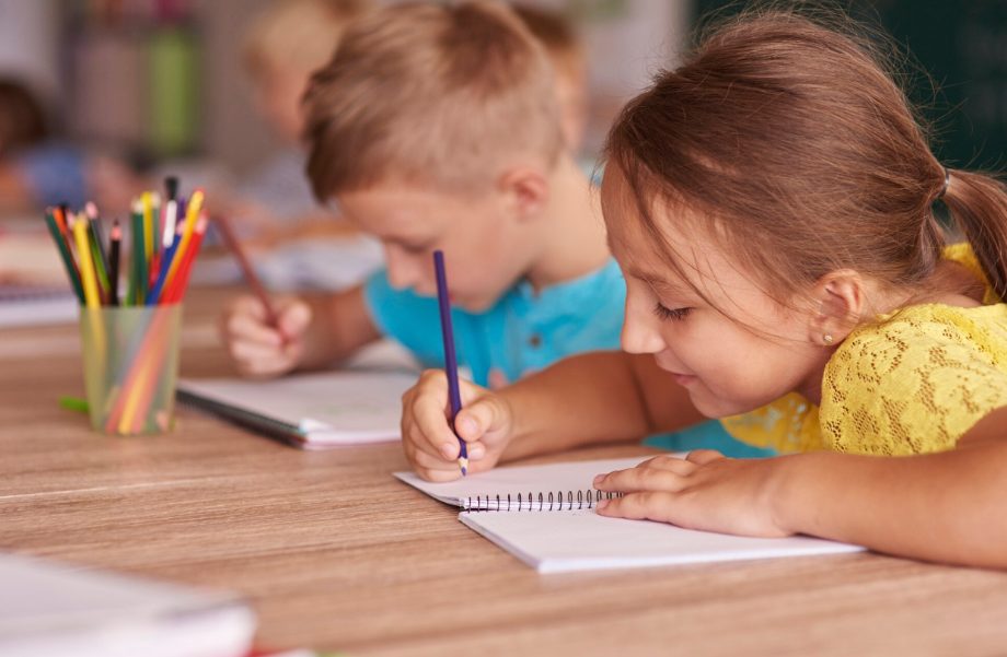 Две деца рисуват с цветни моливи