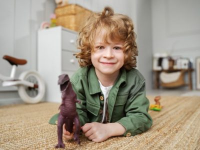 Усмихнато момче си играе с динозавър играчка